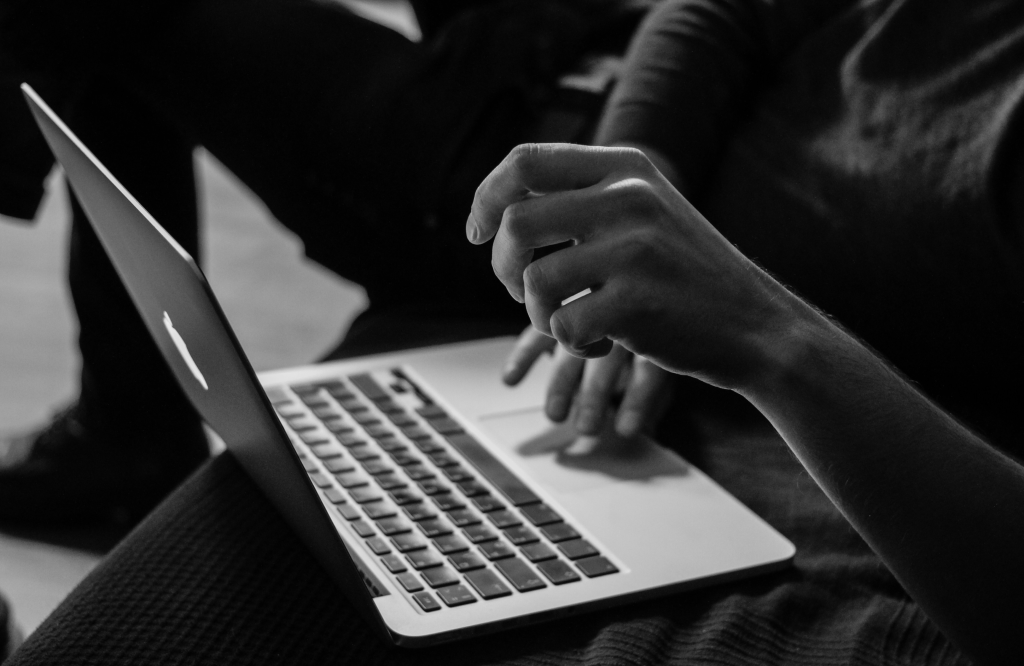 A person works on a laptop, their hands poised over the keyboard.